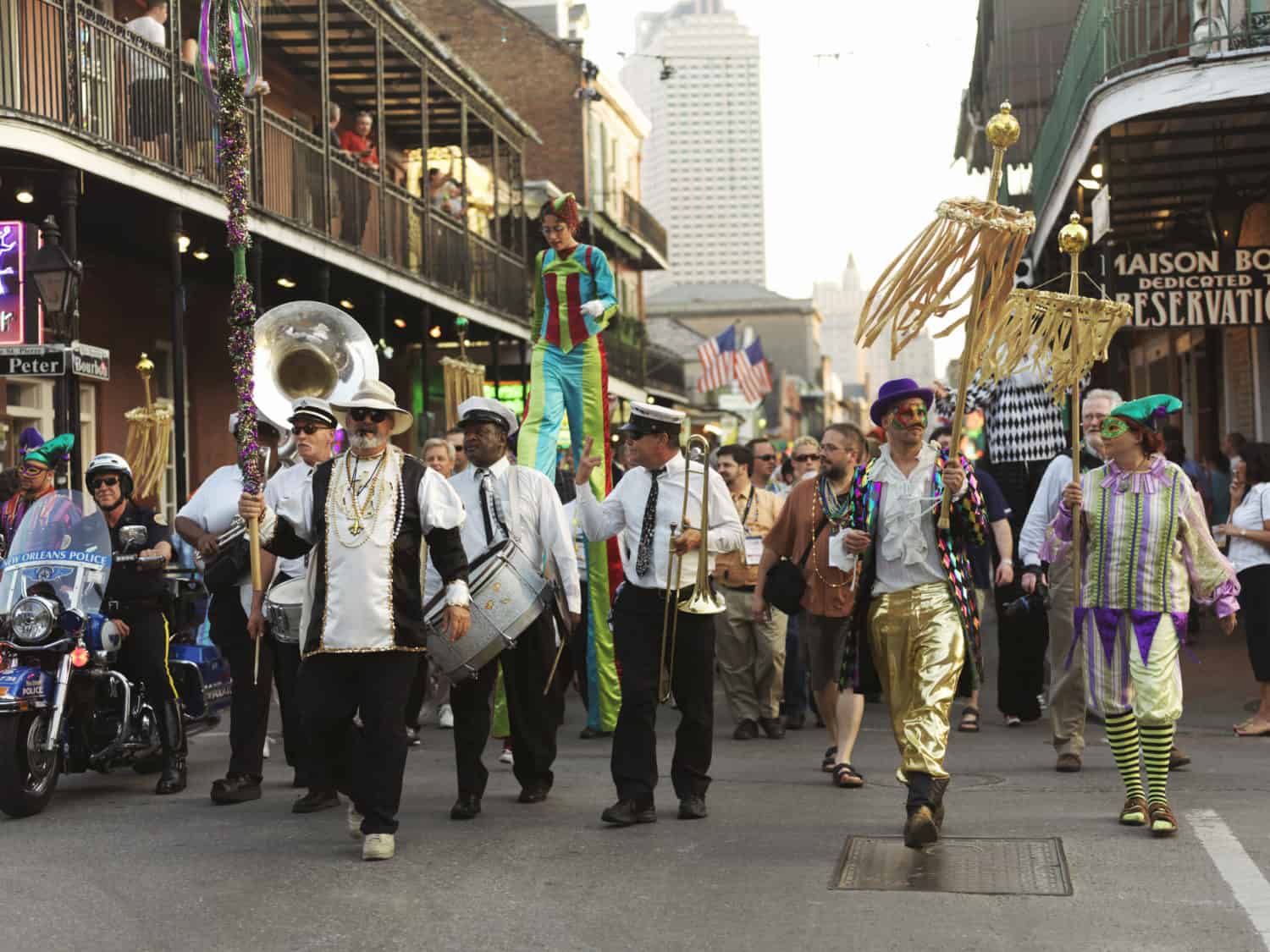 People walking in a parade in New Orleans, led by musicians and people in costumes