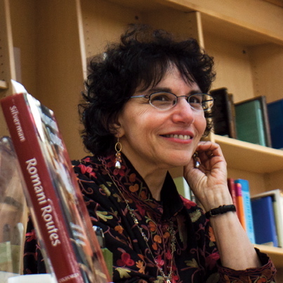 A woman in glasses in semi-profile against a backdrop of books