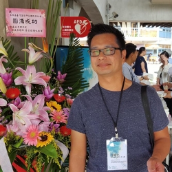 photograph of lee walking in an open air market wearing a badge