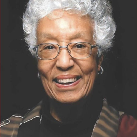 headshot of marilyn white, who has white hair, wears glasses, and has a brown and black striped jacket