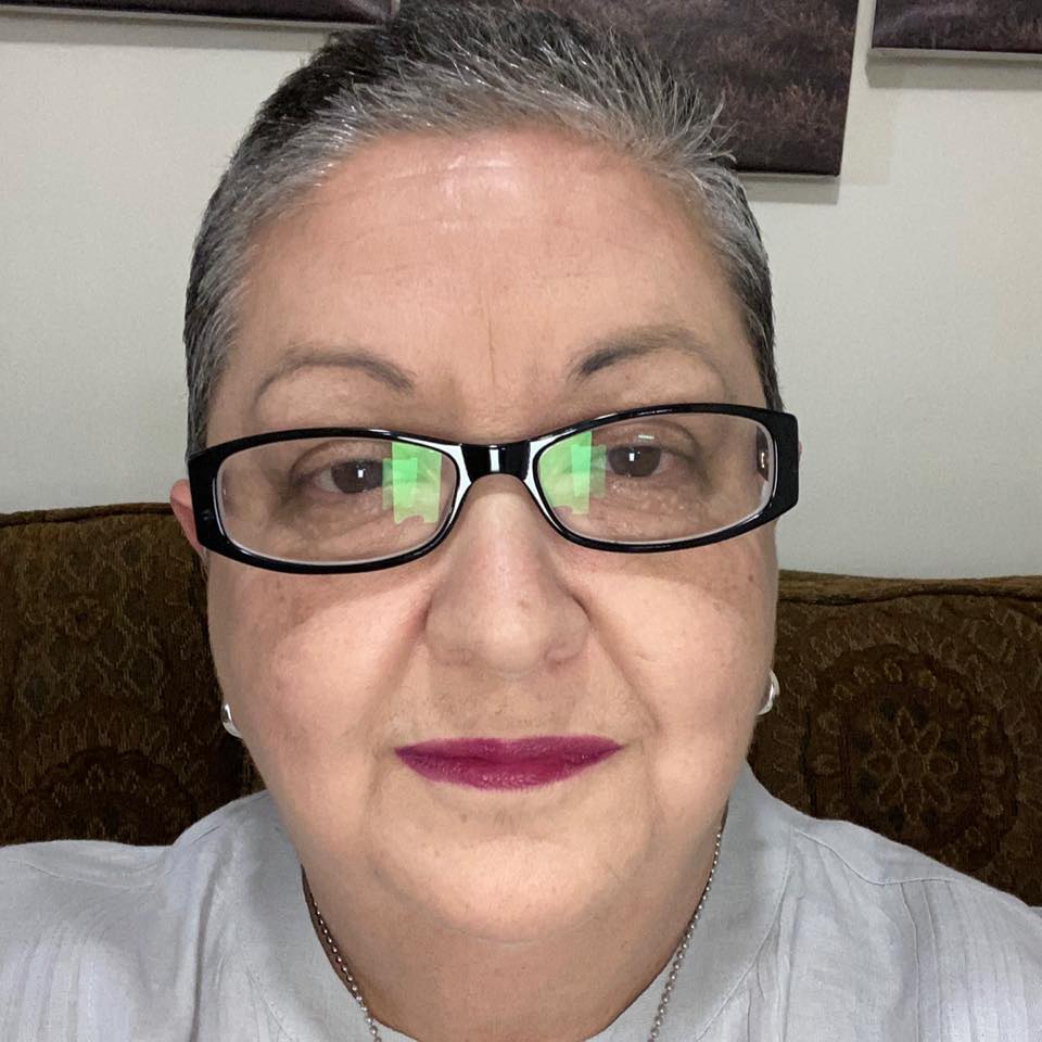 Headshot of Maribel Alvarez, who wears black-frame glasses and a grey shirt