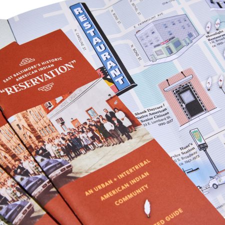 brick red brochures laid out in a fan pattern with an open brochure laid underneath