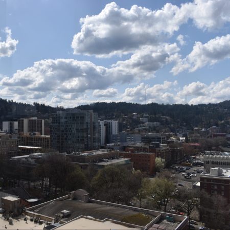 view of portland from the top floor of the portland downtown hilton hotel. the view includes a cityscape, puffy white clouds, and a blue sky